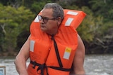 Man wearing glasses and orange lifevest in boat