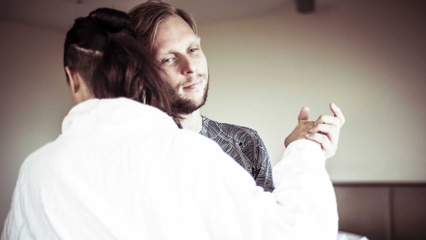 A man dances with a woman in a dressing gown.