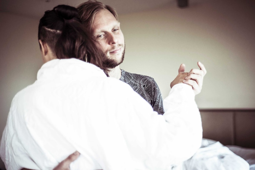 A man dances with a woman in a dressing gown.