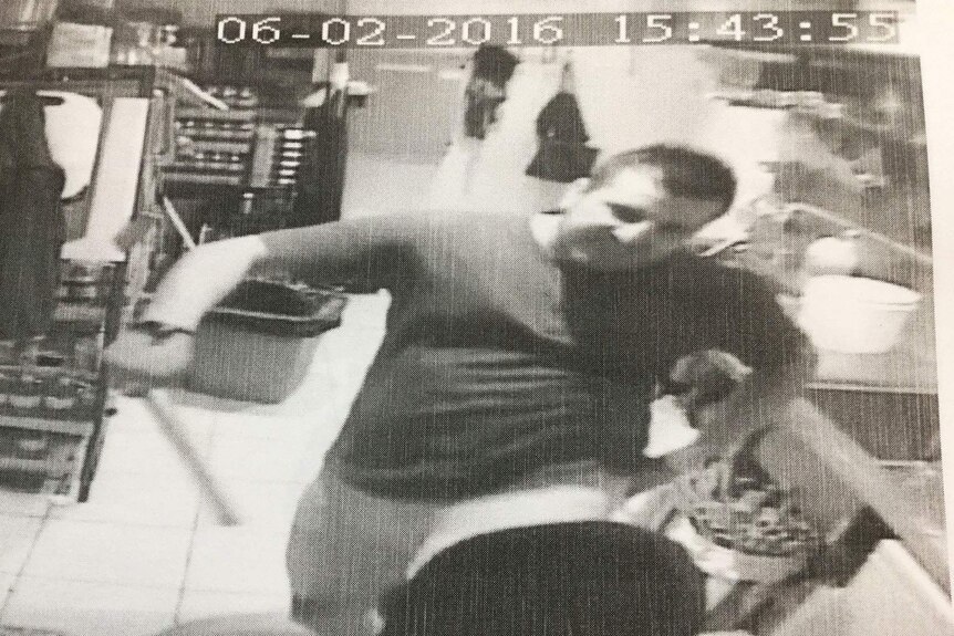 CCTV still of Brisbane kebab shop owner Onur Erkan with a wooden baton assaulting a 15-year-old employee