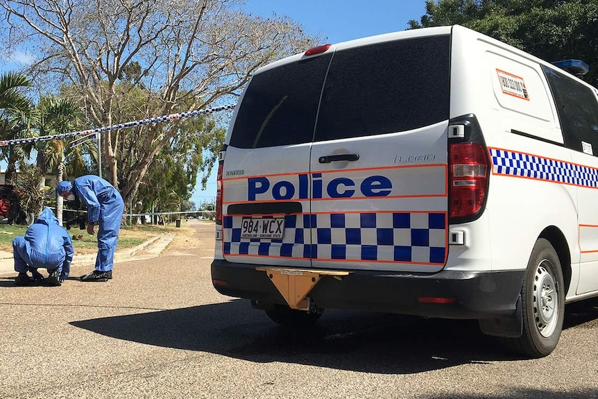 Forensic police officers kneel on road at the scene where two men died at a house at Alva.