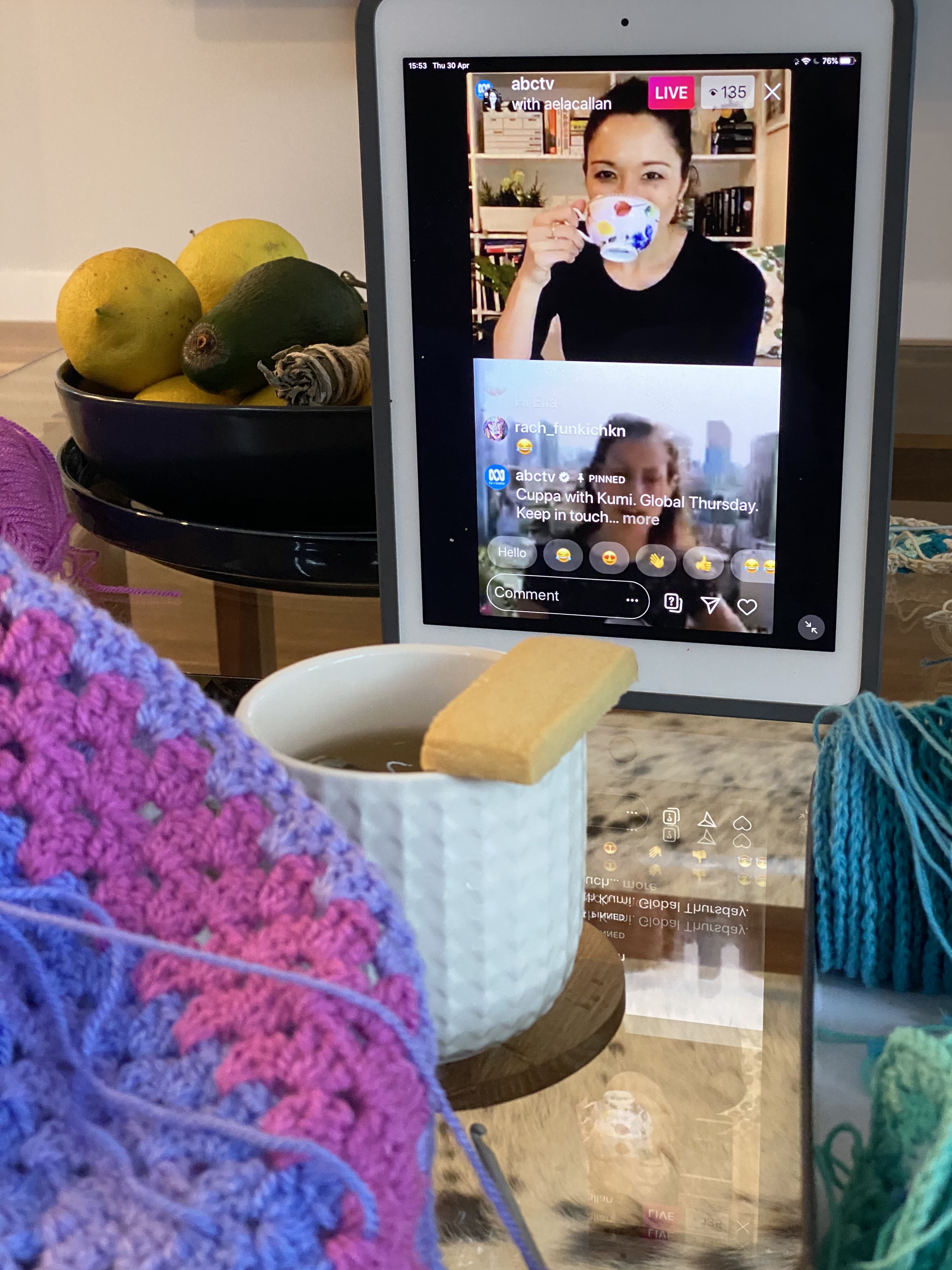 Ipad screen showing Kumi drinking tea on screen with someone being interviewed and cup of tea and shortbread in front.