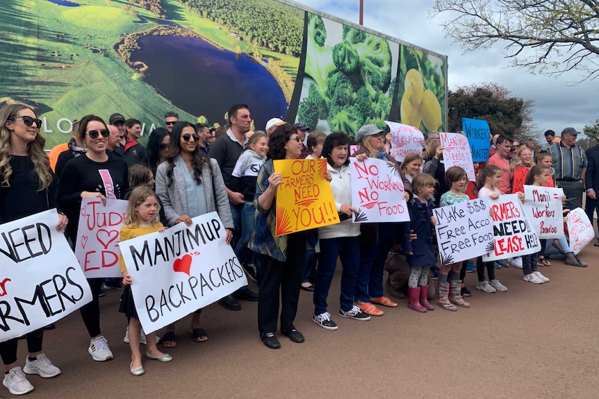 A group of people standing on a street, holding banners with slogan supporting backpackers.