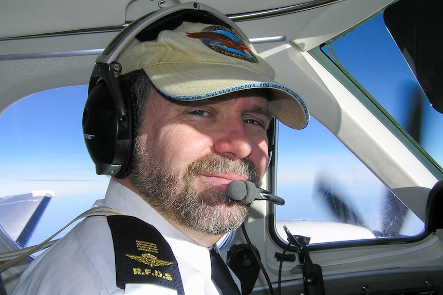 Pilot sitting in a plane with cap on.