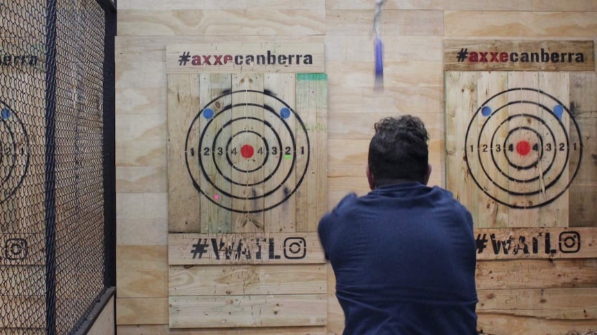 A man hurls an axe at a target.