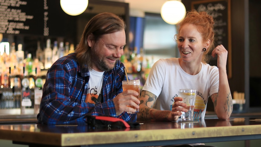 Lindsay McDougall and Jen Owens sit at a bar with non-alcoholic drinks.