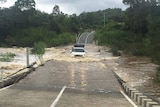 A four-wheel drive crosses a flooded causeway in the Gold Coast hinterland