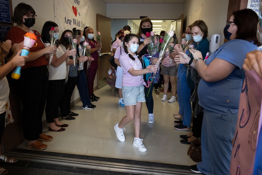 une jeune fille distribue des roses à une foule alors qu'elle quitte l'hôpital