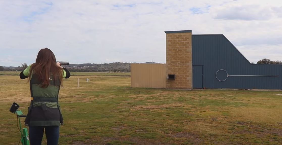 a woman holding a rifle aiming at a target