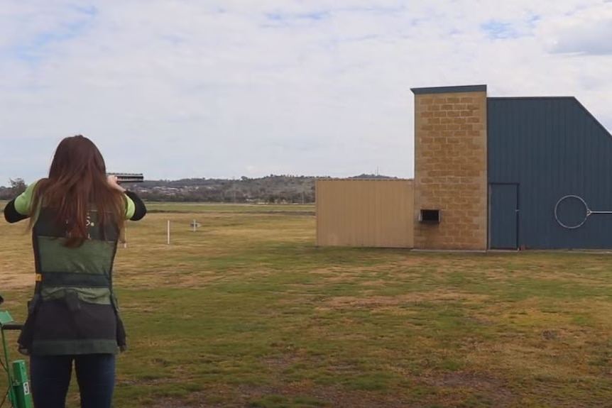 a woman holding a rifle aiming at a target