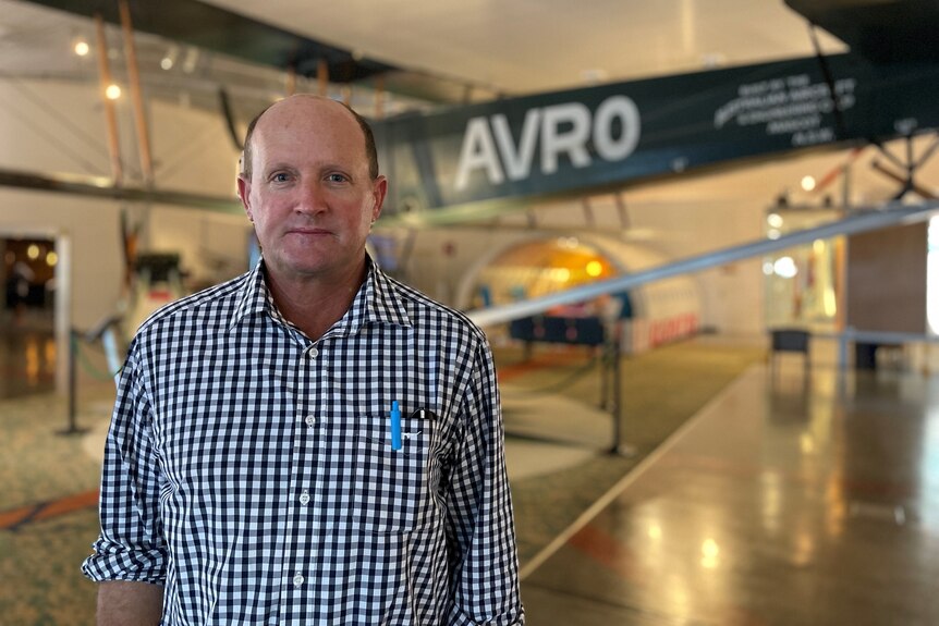 A man stands in an aircraft museum.