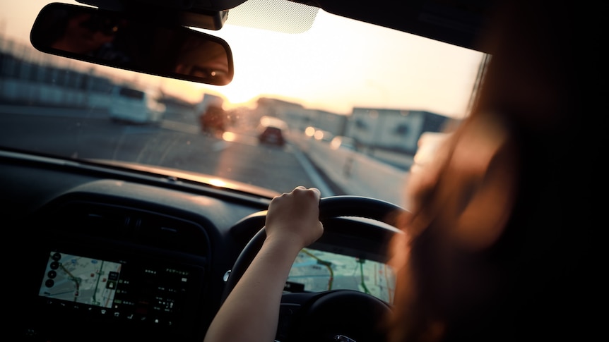 a driver behind the wheel at sunset