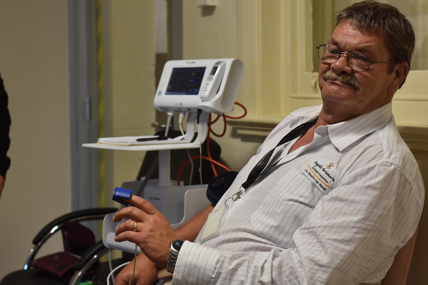 Man sits next to blood pressure machine
