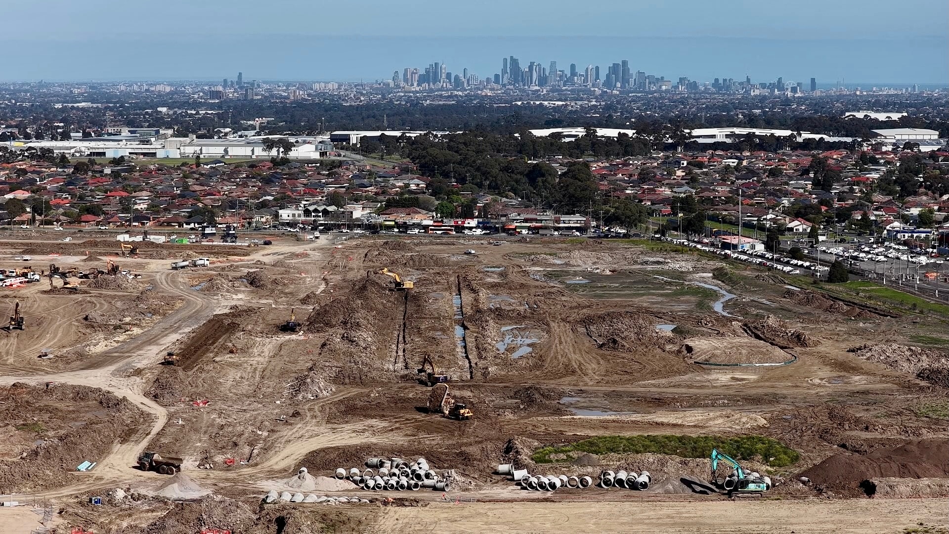 Large expanse of cleared land with city of Melbourne skyscrapers in the background. Blue sky.
