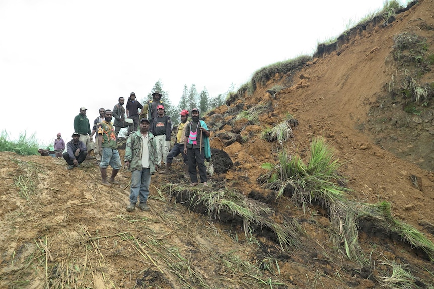 Locals stand on a mound of land that was once a highway