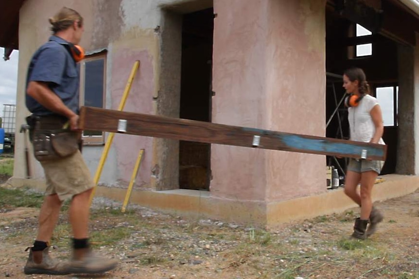 James and Alicia at work on site, carrying a door frame.
