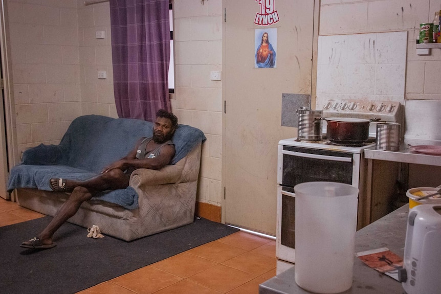 Charlie Lynch sits on a couch in a basic living room.