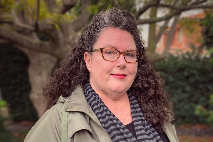 A woman in spectacles in a park.