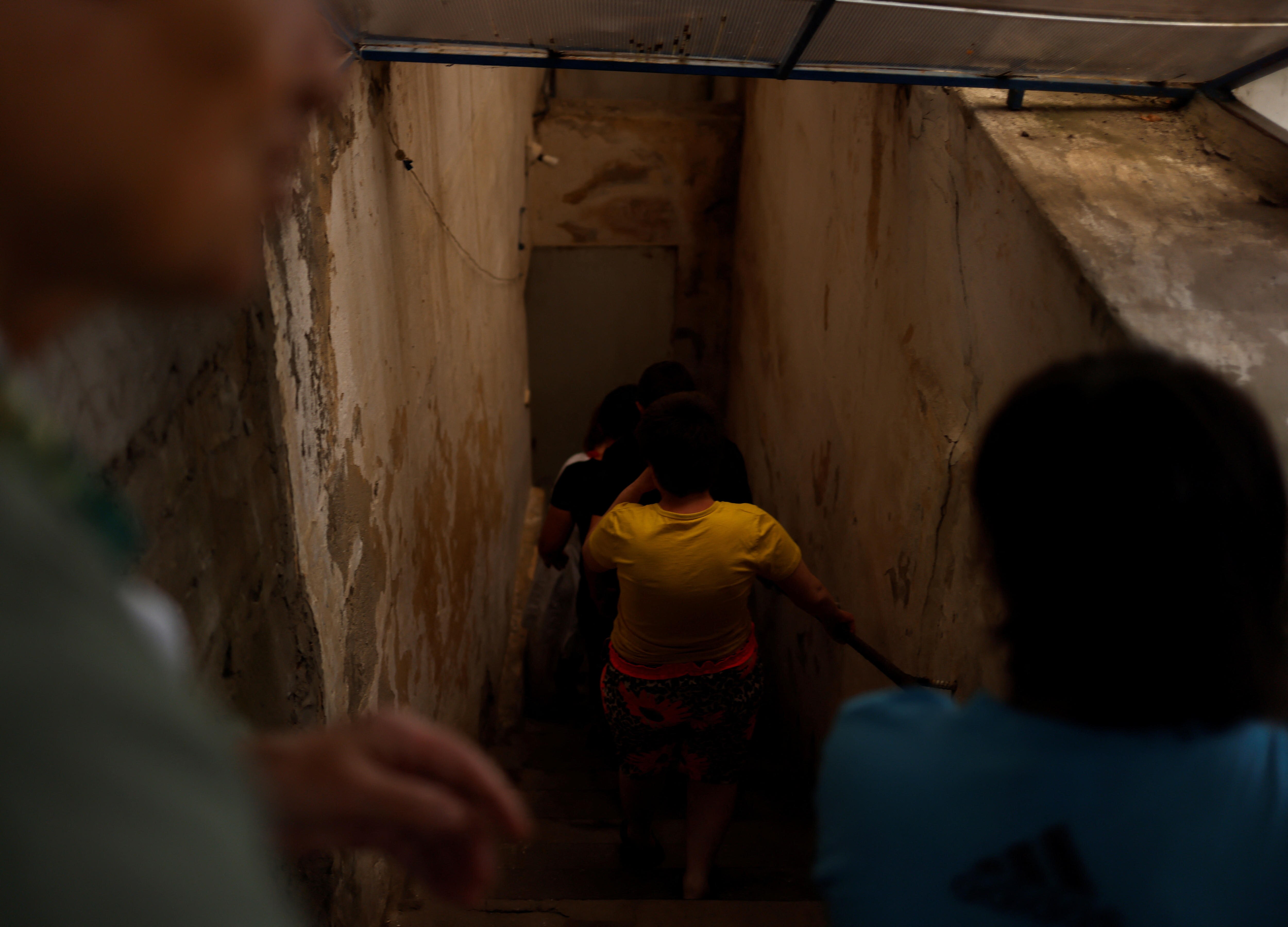 Children take the stairs to a basement shelter at a facility