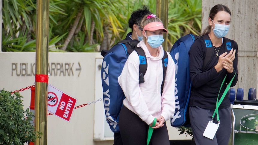 Two female tennis players walk with masks on