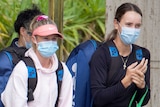Two female tennis players walk with masks on