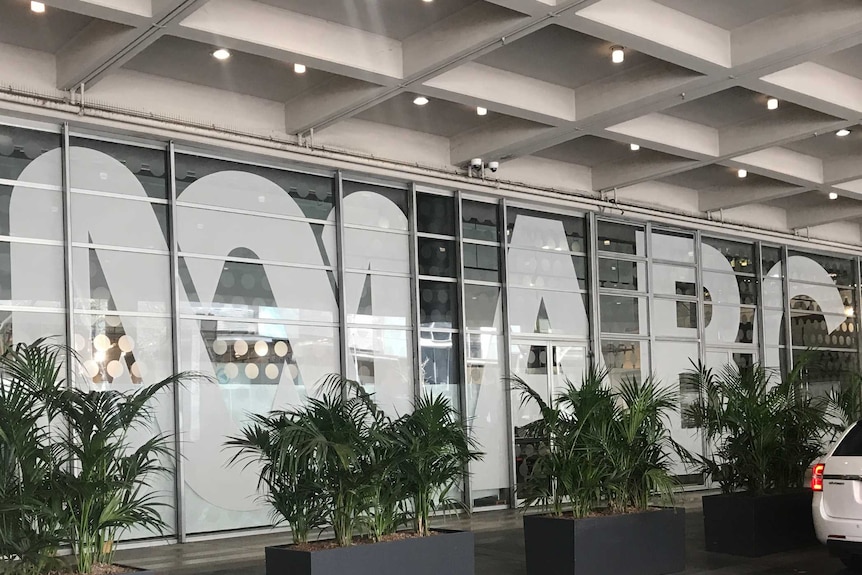 The ABC logo and large white lettering on glass windows with plants in front.