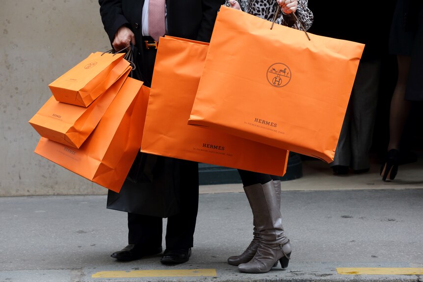 Ein Mann und eine Frau halten viele orangefarbene Einkaufstüten in der Hand