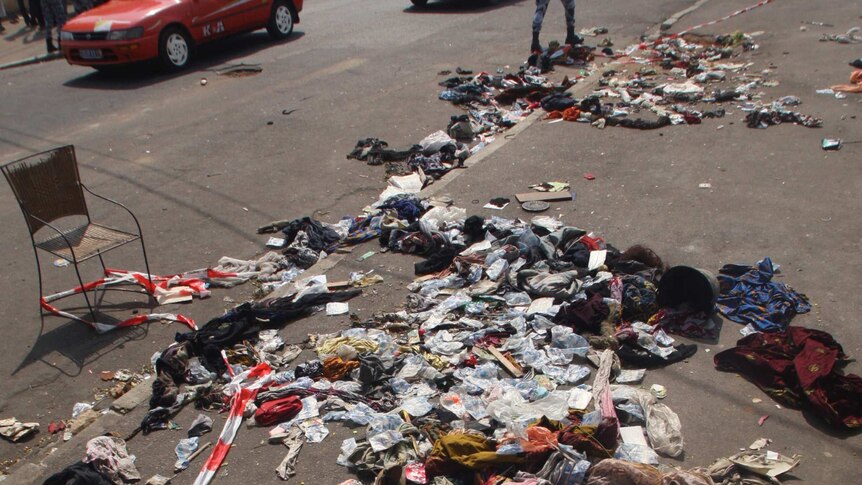 A man walks next to clothing and various items spread over the footpath following a stampede in Abidjan.