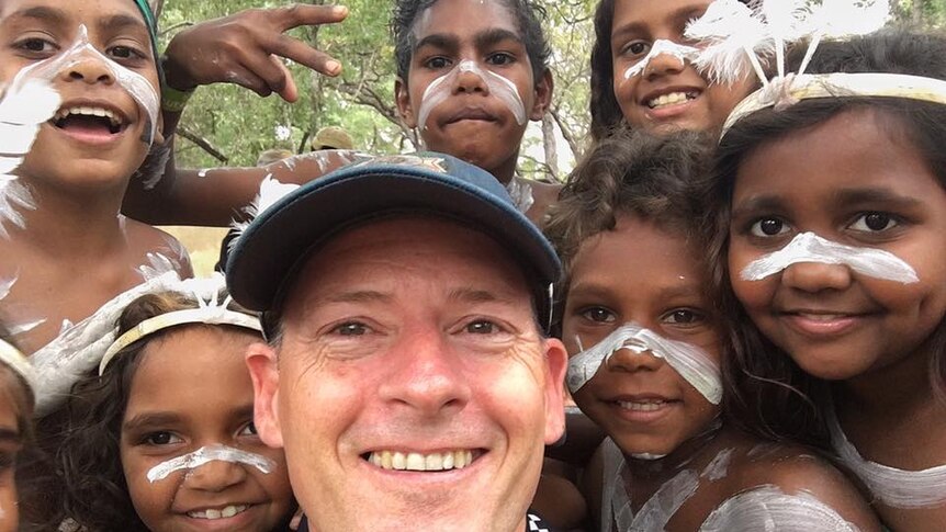 Selfie of police officer surrounded by young Aboriginal dancers in costume.
