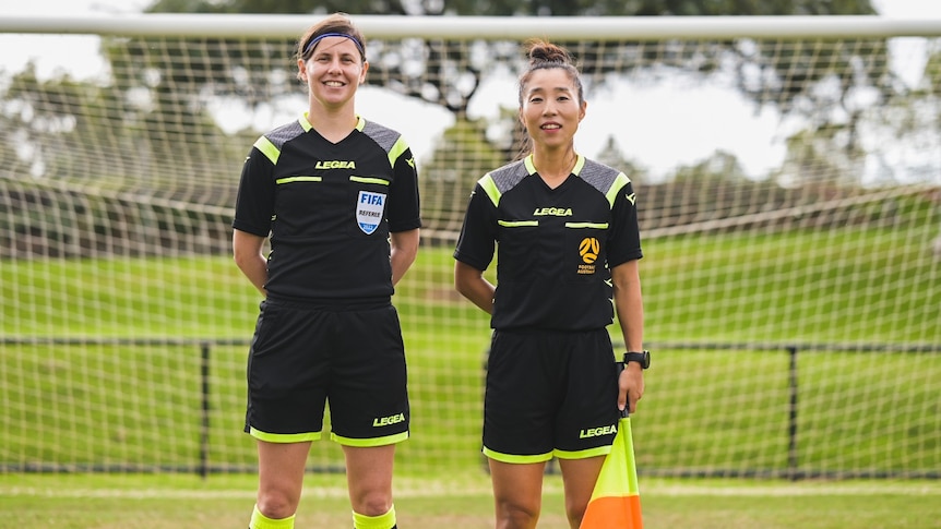 A-League referees Casey Reibelt and Mi Suk Park stand in front of a soccer goal at North Pine football club