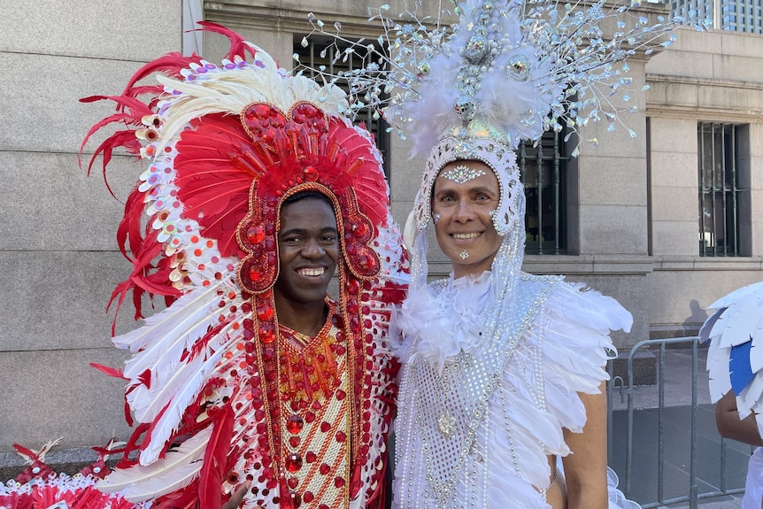 two men wearing headgear and brightly coloured feathers