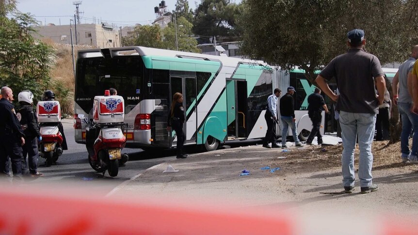 Security and police walk past a bus on which two passengers were killed and four were injured in Jerusalem.