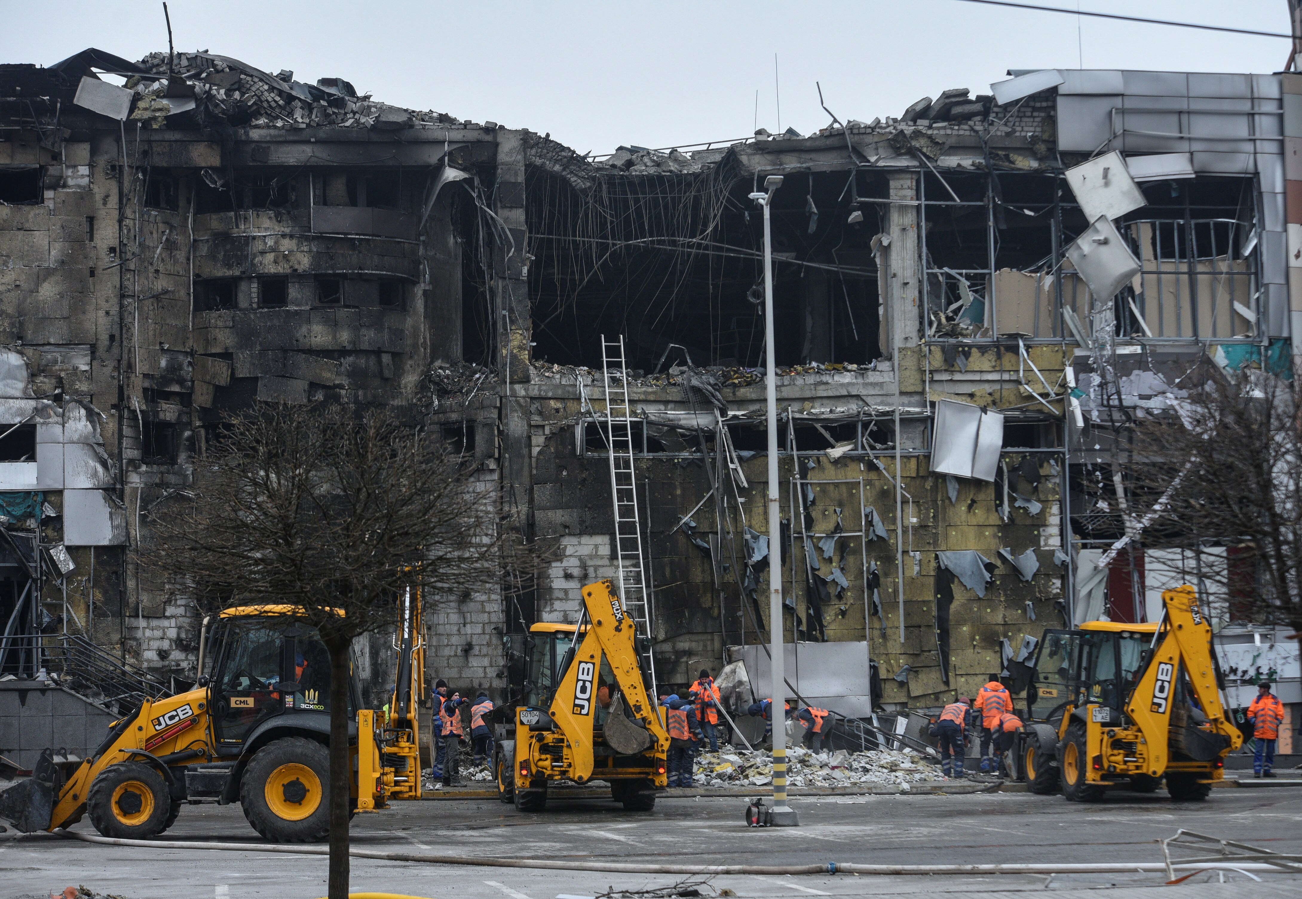 Three tractors near a heavily damaged building, recently hit by an airstrike.