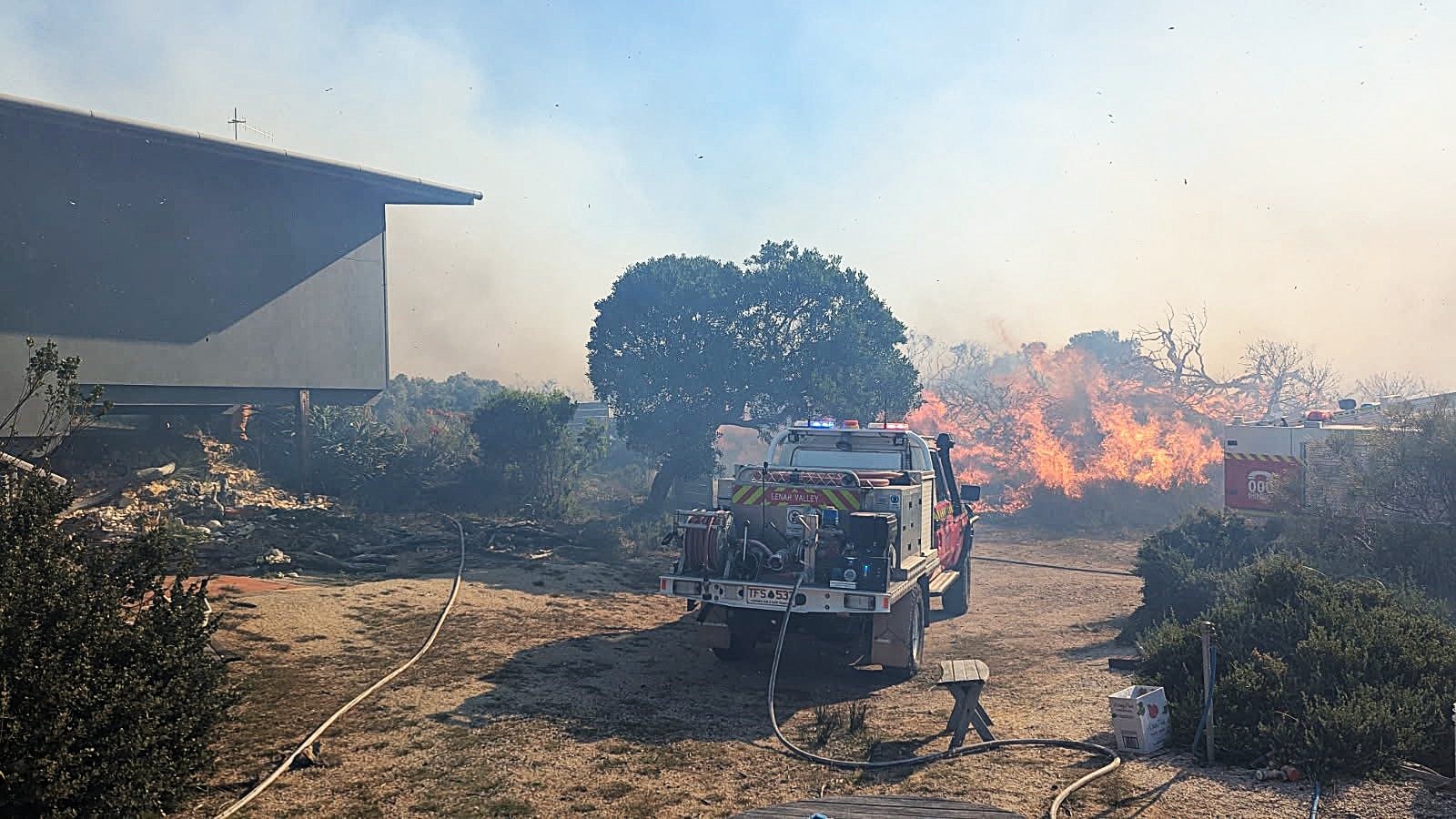 Camión de bomberos del departamento de bomberos cerca de un edificio residencial durante un incendio forestal en Dolphin Sands.