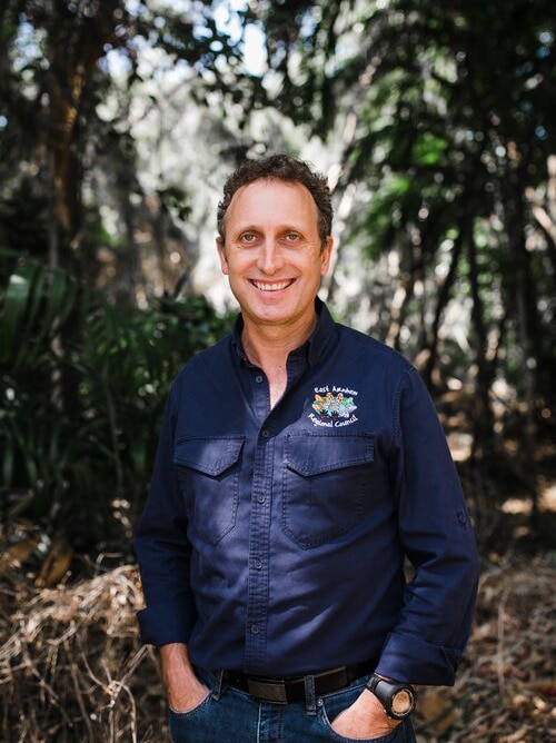 Dale Keehne stands in a monsoon forest and smiles at the camera.