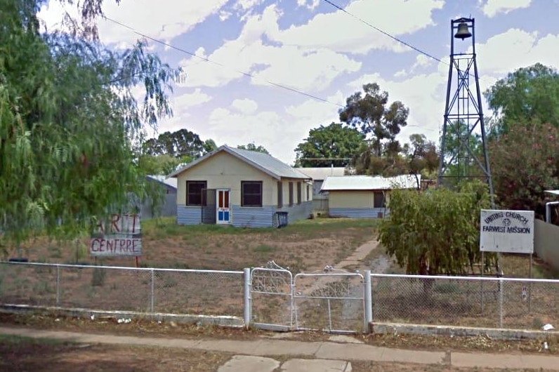 A block of land with a fence with a small house and bell tower on it