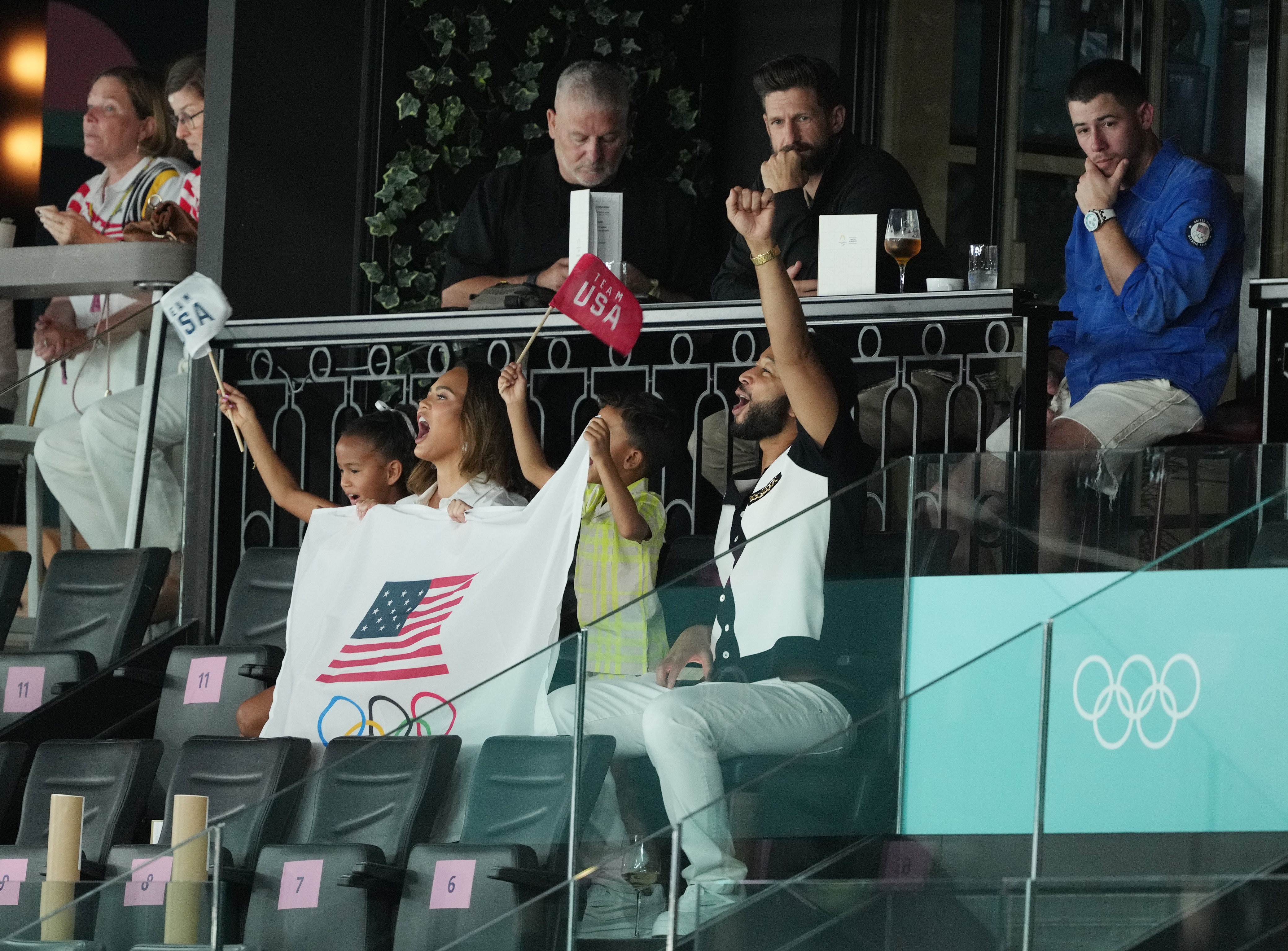 A family of four cheer and wave amercian flags in the grand stand 