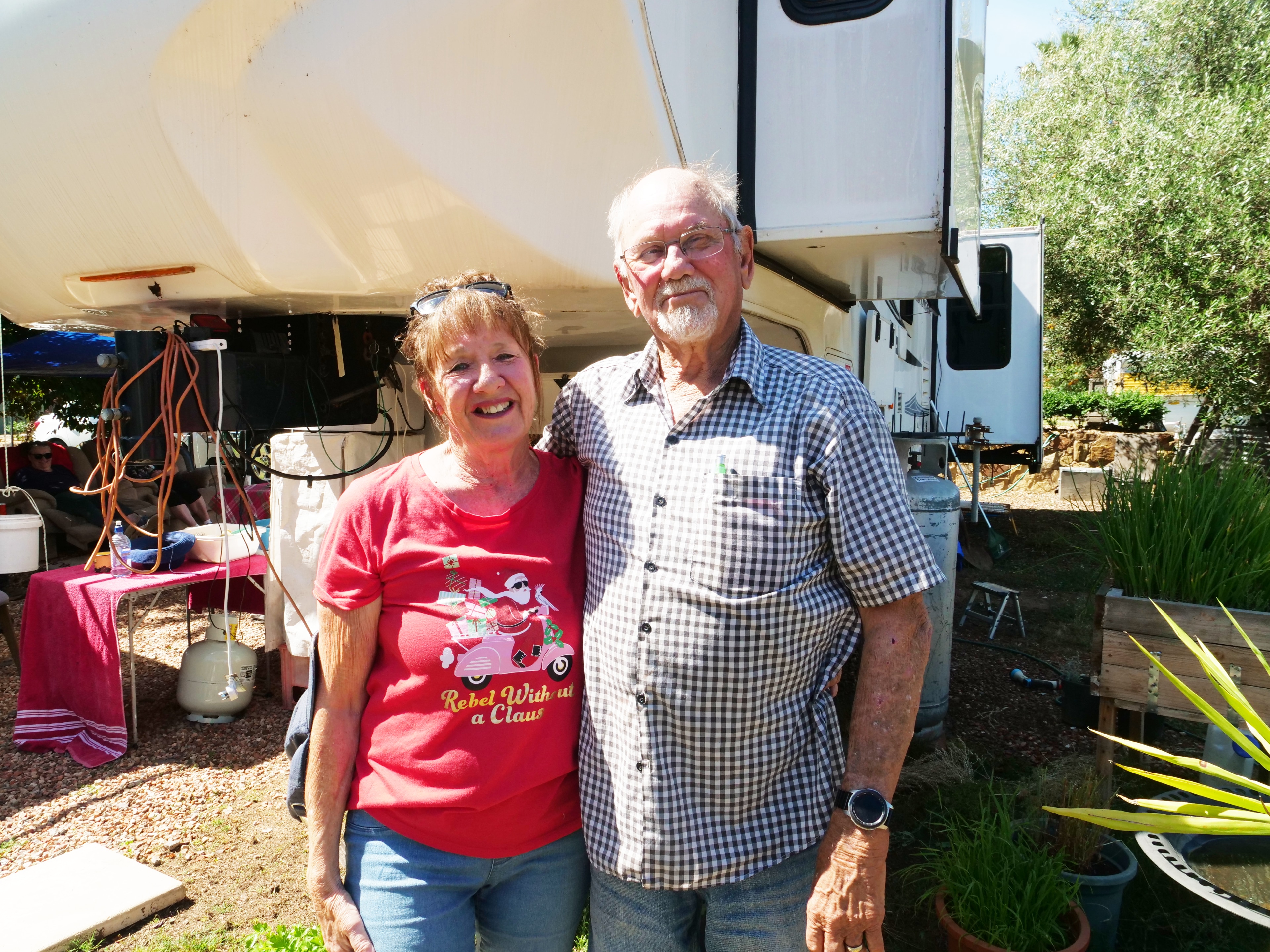 An elderly couple stand in front of their motor home