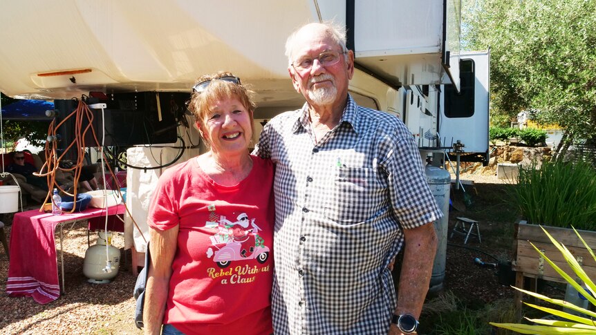 An elderly couple stand in front of their motor home