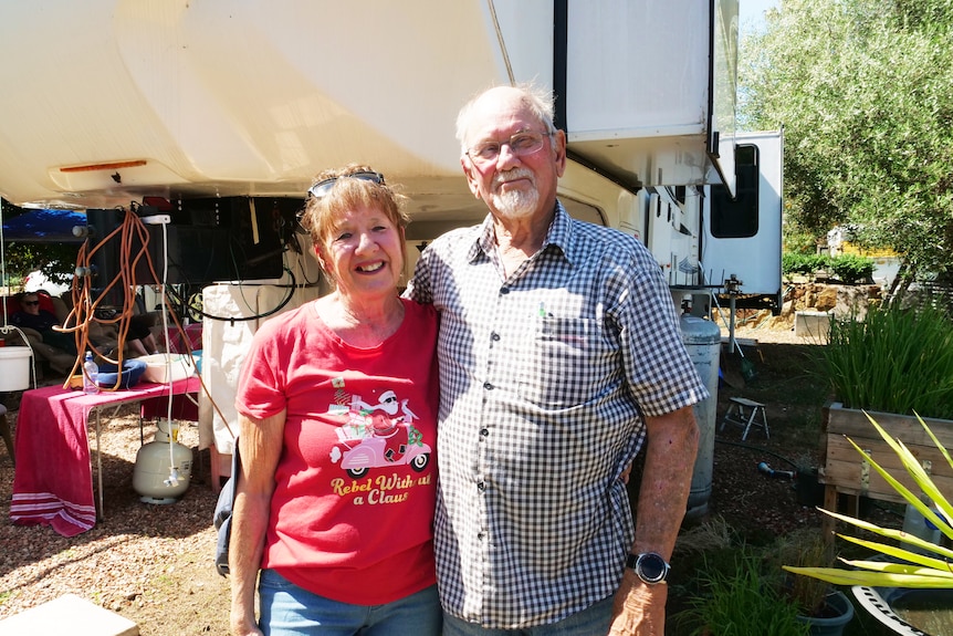 An elderly couple stand in front of their motor home