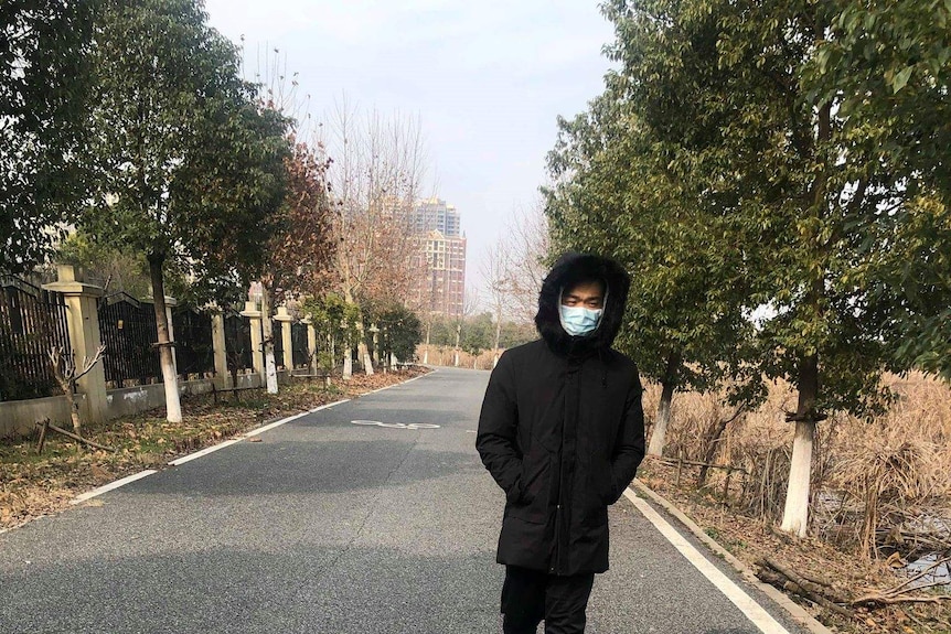 Brian walks down a bike path in a park in Wuhan, with his face covered by a surgical mask.