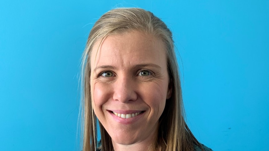 A smiling woman wearing a green blouse against a blue background.