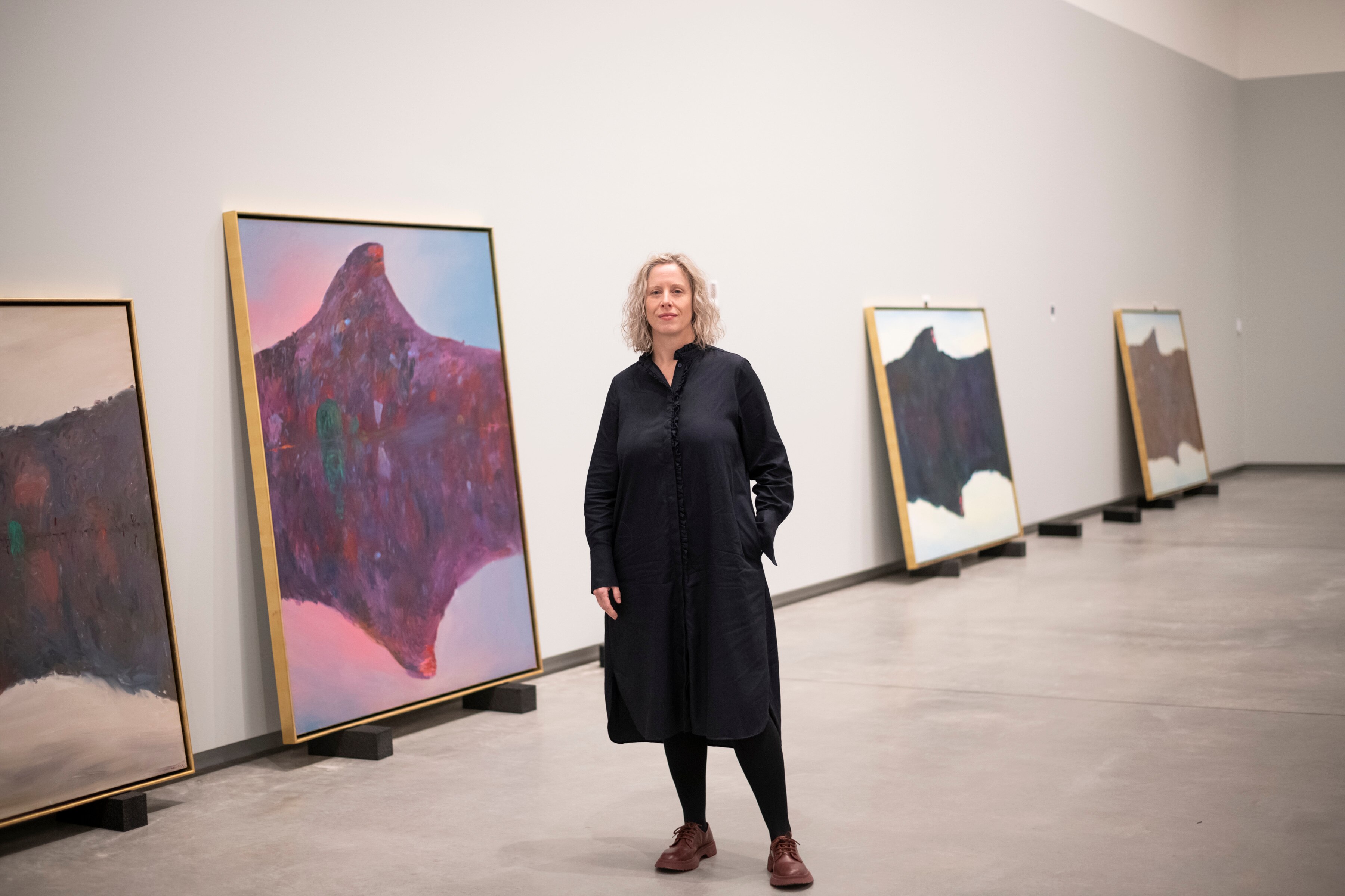 A photo of art curator Sophie O'Brien in front of Arthur Boyd paintings at Bundanon.