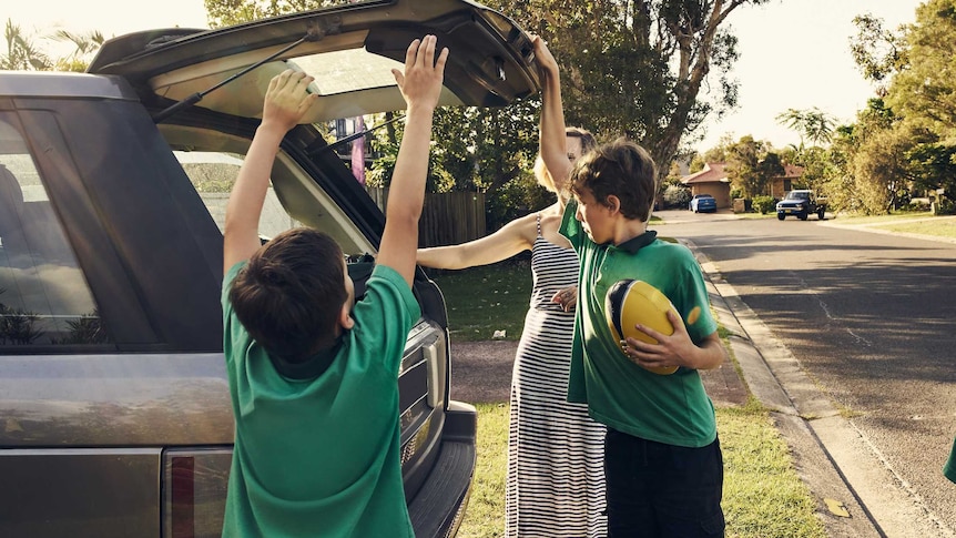 A woman arriving at home with her three sons after picking them up at school.