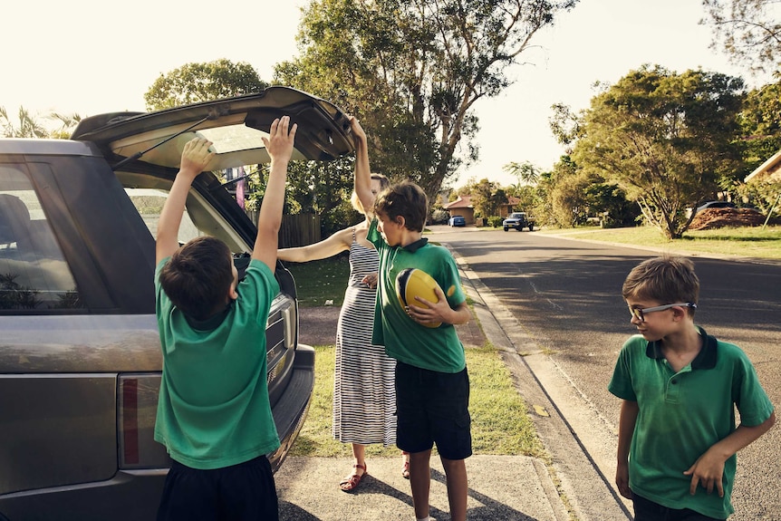 A woman arriving at home with her three sons after picking them up at school.