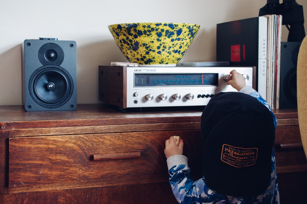 Child in a backwards cap turning the dial on a radio