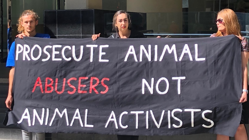 Animal rights activists are standing out the front of Perth Magistrates' Court and are holding a sign