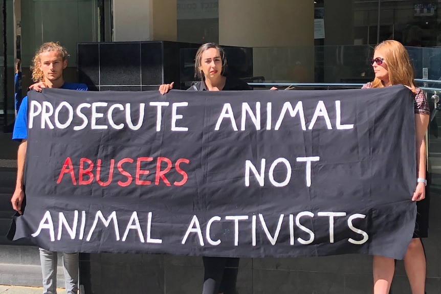 Animal rights activists are standing out the front of Perth Magistrates' Court and are holding a sign