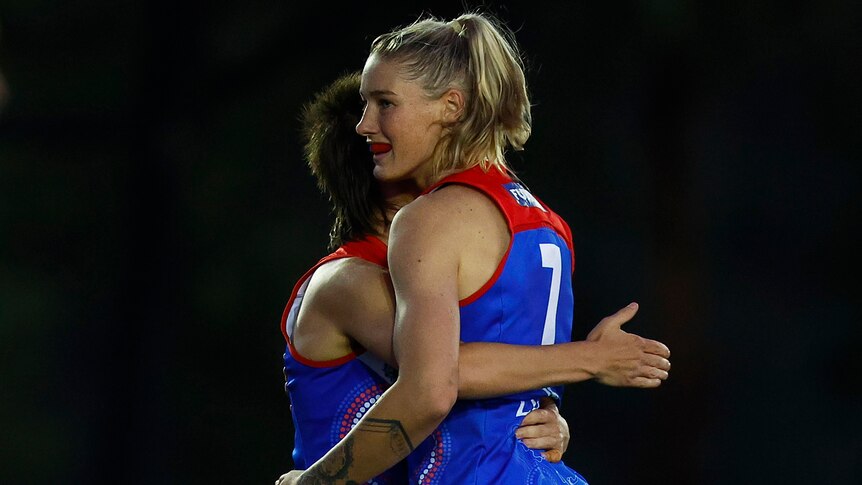 Two Melbourne AFLW players embrace as they celebrate a goal against the Kangaroos.
