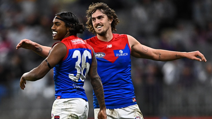 Kysaiah Pickett and Luke Jackson of the Melbourne Demons slap hands during an AFL game.